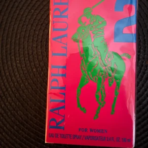 Ralph Lauren 2  för kvinnor - Säljer en Ralph Lauren 2. för kvinnor. Förpackningen är i en livlig röd färg med en grön polospelare och blå text. Flaskan innehåller 100 ml av doften. Helt ny i förpackning 