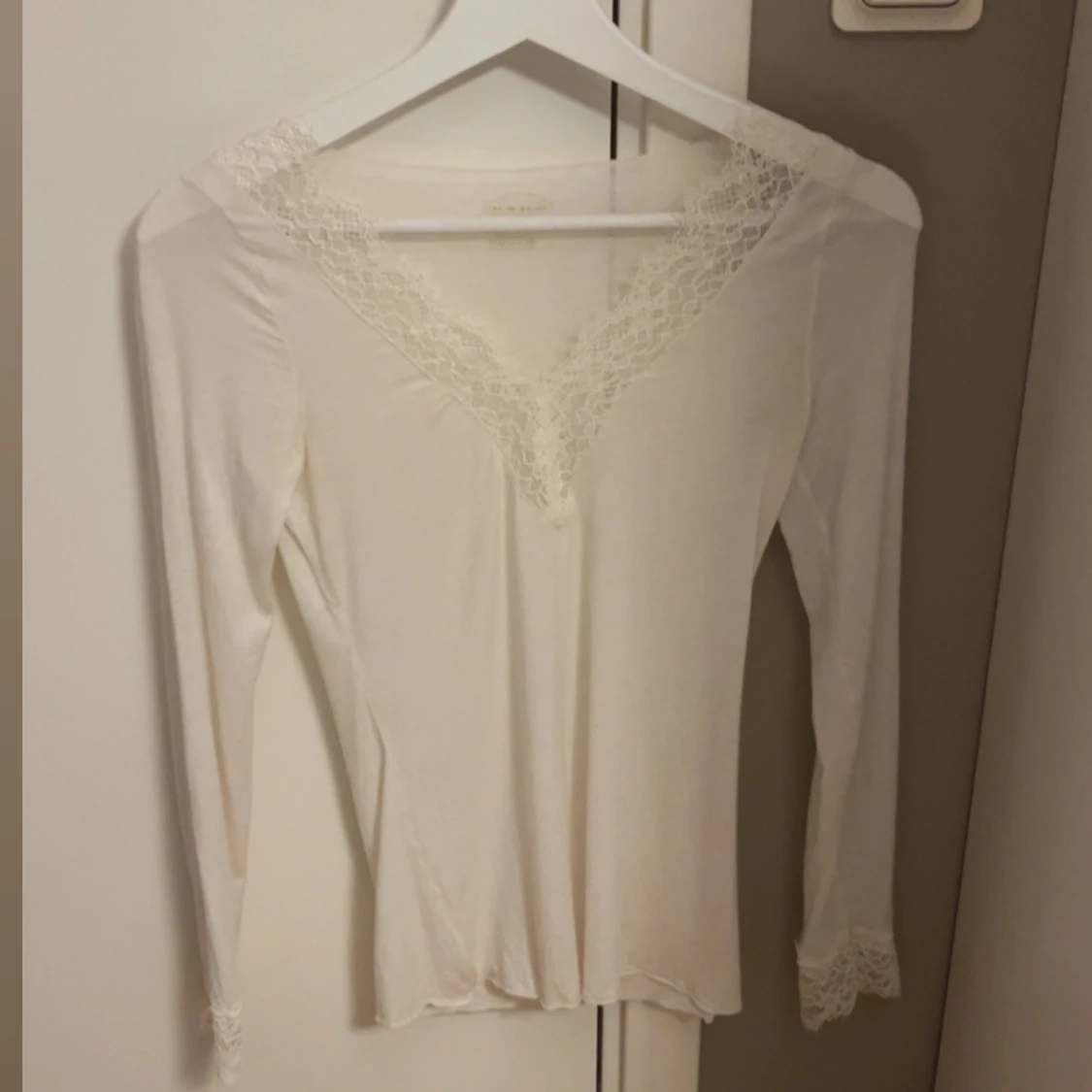 Vit långärmad topp med spetsdetaljer
