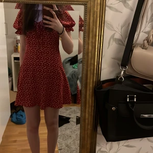 Röd klänning med hjärtmönster från Shein - Säljer en söt röd klänning från Shein med vita hjärtan. Klänningen har en volangdetalj vid axlarna och en dragkedja i ryggen.💕
