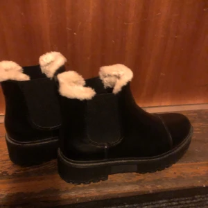 Svarta boots med pälsfoder - Säljer ett par svarta boots med mysigt pälsfoder. De har en robust sula och är perfekta för kyligare dagar. Bootsens stilrena design gör dem lätta att matcha med olika outfits.