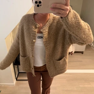 Beige kofta med knappar - Mysig beige/ brun kofta med långa ärmar och dekorativa guldiga knappar framtill. Perfekt för kyligare dagar och ger en avslappnad look. Koftan har två praktiska fickor framtill.😊🥰