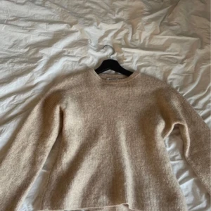 Beige stickad tröja - Säljer en mysig beige stickad tröja med rund hals. Perfekt för kyligare dagar och passar bra till både jeans och kjol. Tröjan har långa ärmar och en enkel design som gör den lätt att matcha med andra plagg.