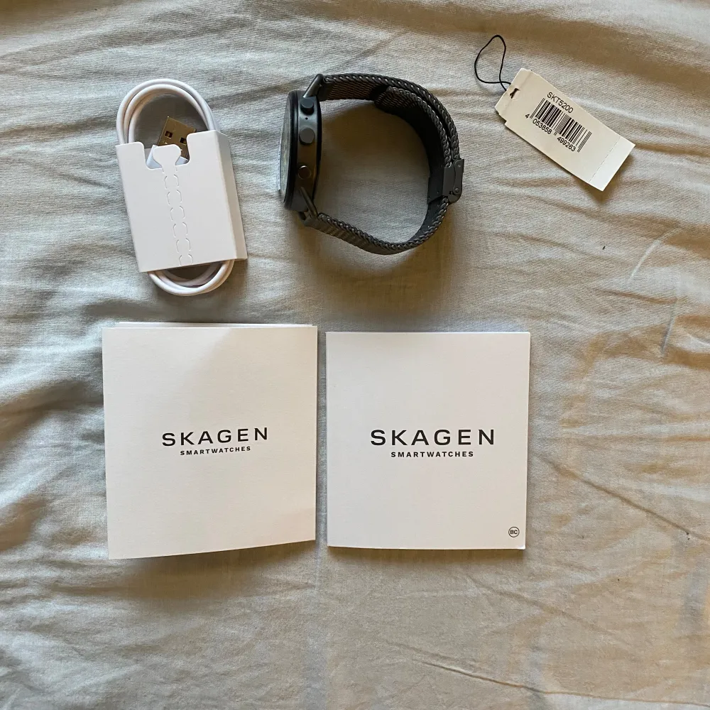 Säljer en snygg och modern svart smartklocka från Skagen. Klockan har en rund urtavla med digital display och ett stilrent armband i svart mesh. Perfekt för både vardag och fest! Klockan kommer med originalförpackning och laddare. Använd en gång. Accessoarer.