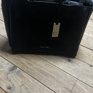 Väska CalvinKlein - Har använts en del. Inköpt på Zalando. Förutom att de korta handtagen har lite skador är den i fint skick