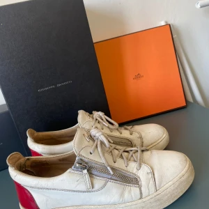 Vita sneakers från Giuseppe Zanotti - Säljer ett par vita Giuseppe Zanotti. De är i skinn och är lite använda i stilen men ändp bra skick, bra skor inför vintern också då dom är lite tjockare i sulan. säljer för jag har skaffat nya skor och har ingen användning till dom mer!
