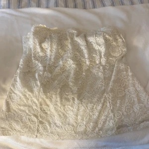 Vit spets tubtopp - En fin crop top med spets i storlek 42C. Är en inbyggd BH i som man kan knäppa själv. Väldigt fin på men för stor för mig och säljer därför!