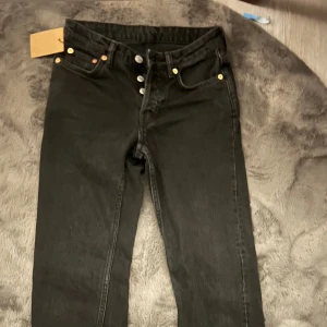 Svarta jeans från Weekday - Snygga svarta jeans från Weekday i modellen Pin Mid Straight. De har knappar i gylfen. Perfekta för en stilren look. Knappt använda! 