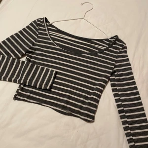 Randig  topp - Säljer en stilren randig topp i grå och vit med långa ärmar. Den är ribbad och croppad, perfekt för en trendig look. Passar bra till både jeans och kjol. Står ingen storlek men gissar på XS. Kontakta mig om du har frågor☺️