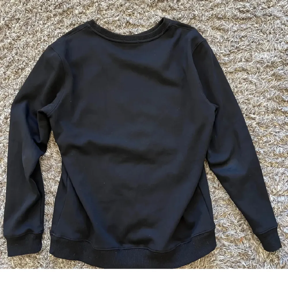 Säljer en stilren svart sweatshirt från Moncler med ett stort broderat logotypmotiv på framsidan. Tröjan har långa ärmar och ribbade muddar vid ärmslut och nederkant. Perfekt för en avslappnad och trendig look. Använd 5-4 gånger . Neuletakit & Villapaidat.