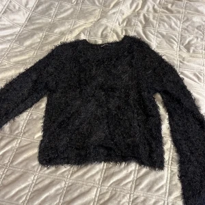 Svart fluffig tröja från Gina Tricot - Säljer en svart fluffig tröja från Gina Tricot. Tröjan har en mysig textur och långa ärmar, perfekt för kyligare dagar. Den är i storlek S och passar bra till både jeans och kjol. Perfekt för att hålla sig varm och stilren.❤️