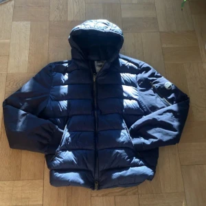 Blå pufferjacka från Colmar - Säljer en snygg blå pufferjacka från Colmar. Jackan har en quiltad design med dragkedja och en praktisk huva. Perfekt för kyligare dagar. Märkeslogga på ärmen ger en extra touch av stil. Passa på att köpa denna trendiga jacka! 💙