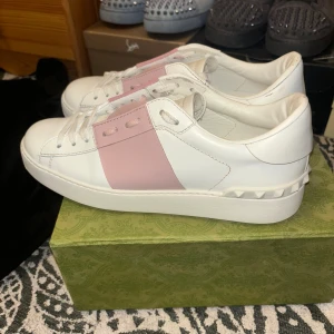 Valentino sneakers med rosa detalj - Snygga Valentino sneakers i vitt med en bred rosa rem över snörningen. Dessa skor är i väldigt bra skick och är väldigt frächa. Cond:9,5/10. Nypris 6200