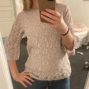 Spetsblus - Säljer en elegant ljusrosa spetsblus från Isolde. Blusen har trekvartsärmar och en fin knäppning i nacken🩷