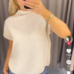 Beige stickad topp - Säljer en stilren beige stickad topp med korta ärmar och hög krage från Lindex. Perfekt för en avslappnad men chic look. Storlek S, aldrig använd. Nypris 299