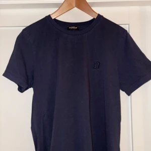 Mörkblå t-shirt från Dondup - Snygg Mörkblå  t-shirt från Dondup med ett diskret broderat 'D' på bröstet. Tillverkad i Italien, perfekt för en stilren look.                                               Storlek M