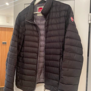 Svart dunjacka från Colmar - Vår jacka från Colmar, välanvänd med ett hål i ryggen men säljer egentligen för att den är för liten. Storlek 50 men känns som en 46 eller 48. Dragkedjorna på fickorna är också lite trasiga.