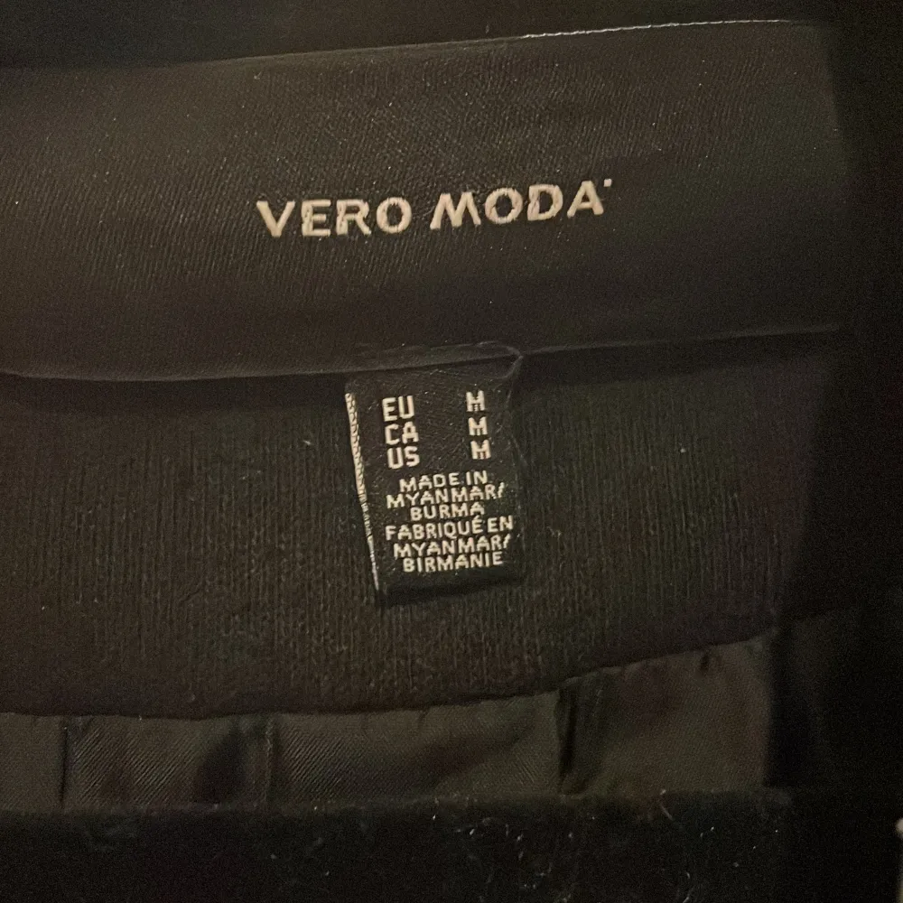 Elegant svart kappa från Vero Moda med knytbälte i midjan. Den har en klassisk design med långa ärmar och är perfekt för kyligare dagar. Kappan är tillverkad i ett mjukt material som ger en stilren look.. Takit.