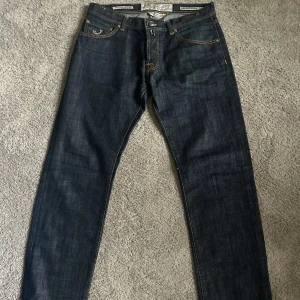 Mörkblå jeansbyxor från Jacob Cohen - Snygga mörkblå jeansbyxor från Jacob Cohen med klassisk femficksdesign och kontrasterande sömmar. Byxorna har en knappgylf och är perfekta för en stilren look. Skick 10/10✅, hör av dig vid frågor… Pris kan diskuteras vid snabb och enkel affär ✅