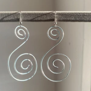 Silvriga spiralformade örhängen - Unika och stilrena örhängen i silver med en elegant spiraldesign. Perfekta för att ge en modern touch till din outfit. Lätta att bära och passar till många olika stilar.