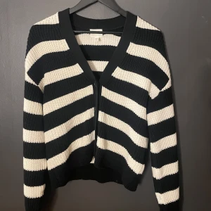 Svart och vit randig kofta från H&M - Säljer en snygg svart och vit randig kofta från H&M. Den är stickad med långa ärmar och har en bekväm passform. Perfekt för att hålla sig varm och stilren under kyligare dagar. Använd denna kofta 2 gånger då den inte passade bra på mig, så är inprincip oanvänd därför väldigt bra skick på koftan! Skriv för bild på!❤️