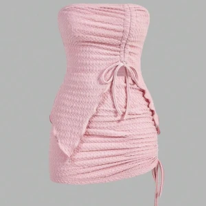 Rosa axelbandslös set - Snygg rosa axelbandslös set med smockdetaljer och knytning framtill. Perfekt för en somrig look med sin korta längd och figurnära passform. Klänningen har en unik design med dragsko på sidan för justerbar längd. Aldrig använd, storlek XXS