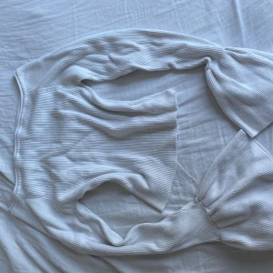 Vit ribbad topp från Gina Tricot - Säljer en stilren vit ribbad topp från Gina Tricot. Toppen har långa ärmar och en croppad design som ger en modern look. Perfekt för att matcha med höga jeans eller kjol.