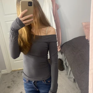  offshoulder topp - Snygg grå offshoulder topp med långa ärmar. Perfekt för en stilren look. Passar bra till jeans eller kjol.