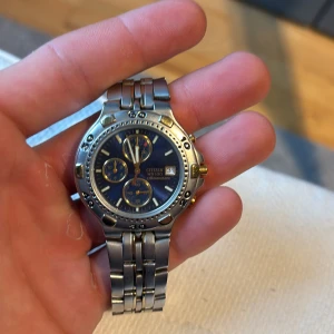Silverfärgad med blå och guld  klocka från Citizen - Snygg och stilren silverfärgad klocka från Citizen med blå urtavla och flera små urtavlor för extra funktioner. Armbandet är i metall och har en klassisk design. Perfekt för den som vill ha en tidlös accessoar.