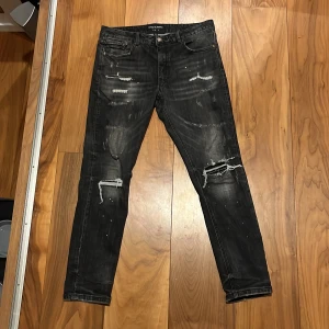 Svarta jeans från Supply & Demand - Snygga svarta jeans från Supply & Demand med slitna detaljer och en cool, distressed look. De är 43 cm rakt över midjan och 101 cm ytterbenslängd. Perfekta för en avslappnad stil med en skön touch.