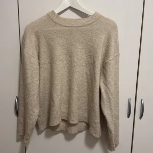 Beige stickad tröja - Mysig beige stickad tröja med långärmad design.