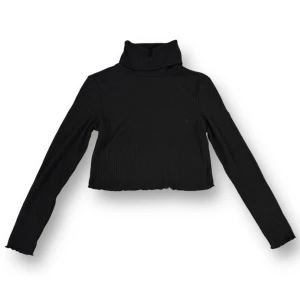 Svart ribbad polotröja från Shein - Säljer en snygg svart ribbad polotröja från Shein. Den är croppad och har långa ärmar, perfekt för en stilren look. Tröjan är i storlek XS och passar perfekt till både vardag och fest. Superbekväm och lätt att matcha med andra plagg!