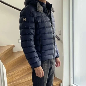 Colmar Vinterjacka - Säljer min knappt använda blåa Colmar dunjacka i storlek 50 (M). Perfekt för vintern med en stilren och användbar jacka. Luvan är avtagbar.   Passar 170-180 långa.  Ordinarie pris: 5189 KR  