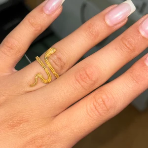 Guldpläterad ring i form av en orm - Säljer en supercool guldpläterad ring i form av en orm. Den är gjord av rent silver med en guldplätering och har en snygg, detaljerad design som verkligen sticker ut. Perfekt för att ge din outfit en edgy touch!