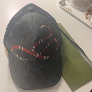 Gucci keps  - Säljer en Gucci keps i storlek xs men den sitter som S då den har en justerbar rem baktill. Kepsen är äkta och kvitto, låda och Gucci kassen medföljer! 