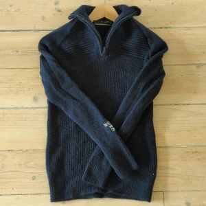 Mörkblå stickad tröja från Neo Mondo - Säljer en snygg och varm mörkblå stickad tröja från Neo Mondo. Den har en dragkedja vid halsen och långa ärmar. Perfekt för kyliga dagar och passar bra till både vardag och utomhusaktiviteter. Tröjan är i nyskick, aldrig använd!