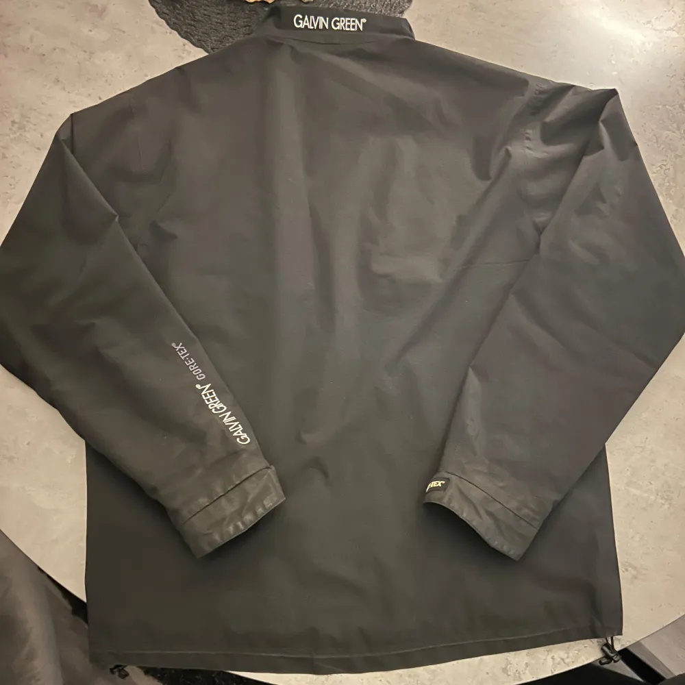 Säljer en svart vindjacka från Galvin Green i storlek M. Jackan är tillverkad i GORE-TEX-material som ger fullständigt skydd mot vind och regn. Den har en dragkedja framtill och långa ärmar. Perfekt för blåsiga och regniga dagar!. Jackor.