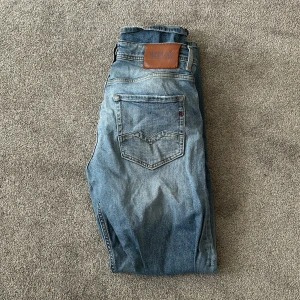 Blå jeans från Replay - Säljer ett par snygga blå jeans från Replay, modell Rocco. De har en klassisk femficksdesign och en ljus tvätt som ger en avslappnad look. Perfekta för både vardag och fest!