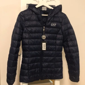 Armani dunjacka stl M Ny!! - Helt ny snygg jacka för höst vår och mildare vinterdagar ( lättvikts dunjacka) känns knappt att du har den på :) Mörk blå  Helt ny med taggs kvar - kan disk pris vid snabb affär / även byte mot likvärdig stl L Följer även med en dustbag 