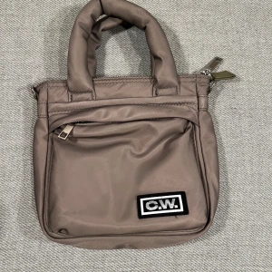 C.W väska - C.W väska som har Axel band som man kan ändra längd på 2 små fickor på insidan och en på utsidan. Den har lite små skrap inget stort. Original pris är 400 säljer för 250.
