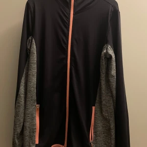  träningsjacka - Säljer en svart och grå träningsjacka från H&M i storlek 170. Jackan har en dragkedja i rosa och en huva. Perfekt för träning eller som en lätt jacka under hösten. Ärmarna är långärmade och materialet känns mjukt och bekvämt.( dock att ena fickan går inte att stänga)