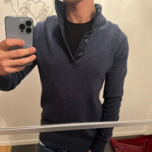 Mörkblå tröja med knappar - Säljer en snygg mörkblå tröja med knappar. Perfekt för både vardag och lite finare tillfällen. Tröjan har långa ärmar och en skön passform. Passar perfekt till jeans eller chinos!