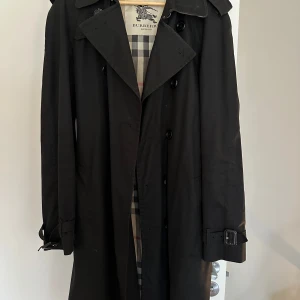 Burberry Trenchcoat Kensington - Burberrys klassiska trenchcoat Kensington.  Svart. Stl 50. Fint skick.  Köpt i Burberry butik. 