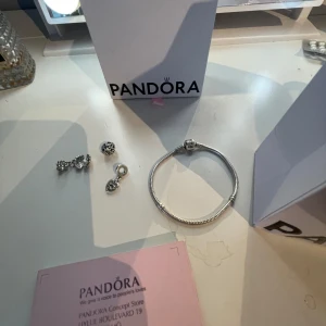 Pandora armband - Säljer mitt Pandora armband då det inte kommer till användning. Hyfsat nytt köpt i våras. Tillkommer med tre berlocker var två av de ockwå är från Pandora. Tillkommer box och påse från Pandora. Armbandet är 18cm💞