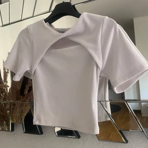 T-shirt  - Snygg vit T-shirt med design liten öppning vid bröstet.