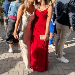 Röd långklänning med volanger - Röd lång balklänning med volanger och smala axelband. Klänning har även en slits vid högerbenet som börjar strax nedanför knät. Använd en gång så skulle säga att den är som ny. Pris kan absolut diskuteras❣️ 