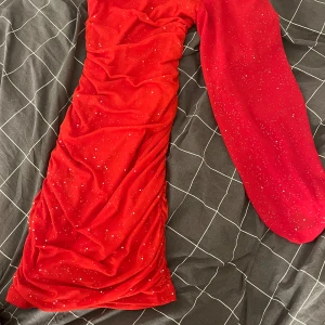 Röd glittrig klänning - Snygg röd klänning med glittriga detaljer. Den har en tight passform och är axelbandslös, vilket ger en elegant look. Perfekt för festliga tillfällen🎈Den är  i storlek XS och inte kommit till användning en enda gång! Därför säljs den.