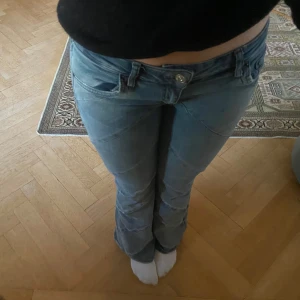 Blå bootcut jeans från BDG - Säljer dessa snygga coola unika blå bootcut jeans från BDG med en unik snedställd sömdesign. De har en klassisk femficksmodell och knäppning med dragkedja. Perfekta för en avslappnad stil med en twist. W28 L32 säljer då de är en aning för korta på mig i min smak💕 sååå snygga, de har lite defekter längst ner på baksidan som man ser på sista bilden!💕