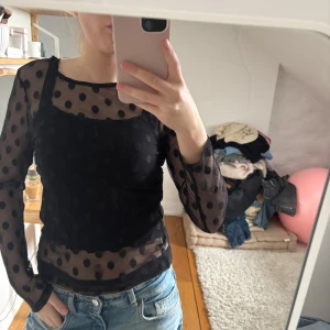 Svart prickig mesh-topp från Zara - Snygg svart mesh-topp från Zara med prickigt mönster. Toppen har långa ärmar och en tight passform, perfekt för en trendig look. Den är genomskinlig och kan stylas med ett linne under för en cool effekt.