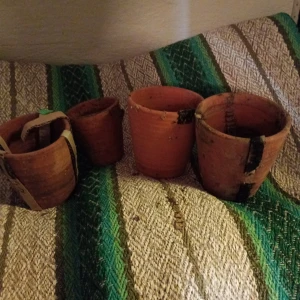Terrakotta krukor olika storlekar. - Fyra terrakottakrukor i olika storlekar, perfekta för plantering. De har en rustik känsla och är placerade på en grön- och vitrandig filt.