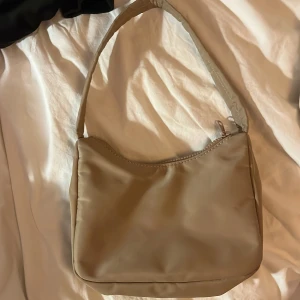 Beige axelväska från Gina Tricot - Snygg beige axelväska från Gina Tricot med dragkedja upptill. Använd ett fåtal gånger men ändå i väldigt bra skick.😊